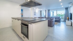 A modern kitchen with a central island, built-in oven, and stainless steel range hood. - HT RTA Sole Dell'Argentario (Porto Santo Stefano)