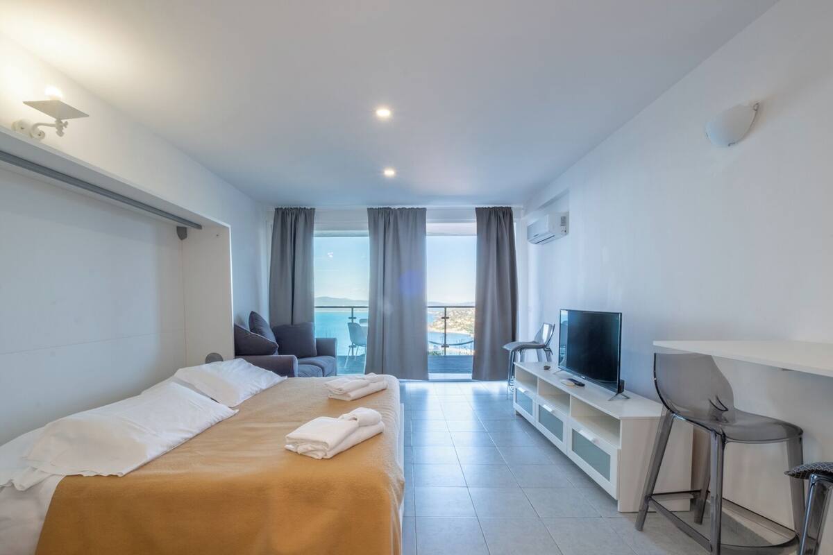 Una camera d'albergo con un letto, una televisione, una scrivania e un balcone con vista.