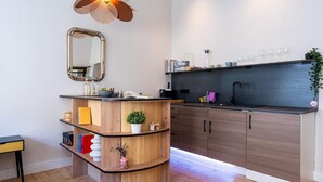 A modern kitchen with wooden cabinetry, a black countertop, and a built-in sink. There is a mirror above the countertop and a shelf with books and decorative items. - Apartment in Koblenz near Deutsches Eck (Koblenz)
