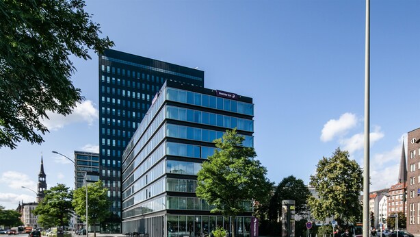 A modern hotel with a glass facade, a prominent Premier Inn sign, and a traditional church spire in the background. - Premier Inn Hamburg City Zentrum (Hamburg)