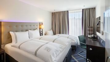 Une chambre d’hôtel avec un lit double, un bureau avec une chaise, une télévision et une fenêtre avec des rideaux.