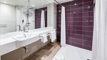 Ein modernes Badezimmer mit zwei Waschbecken, einer Dusche und einem großen Spiegel.