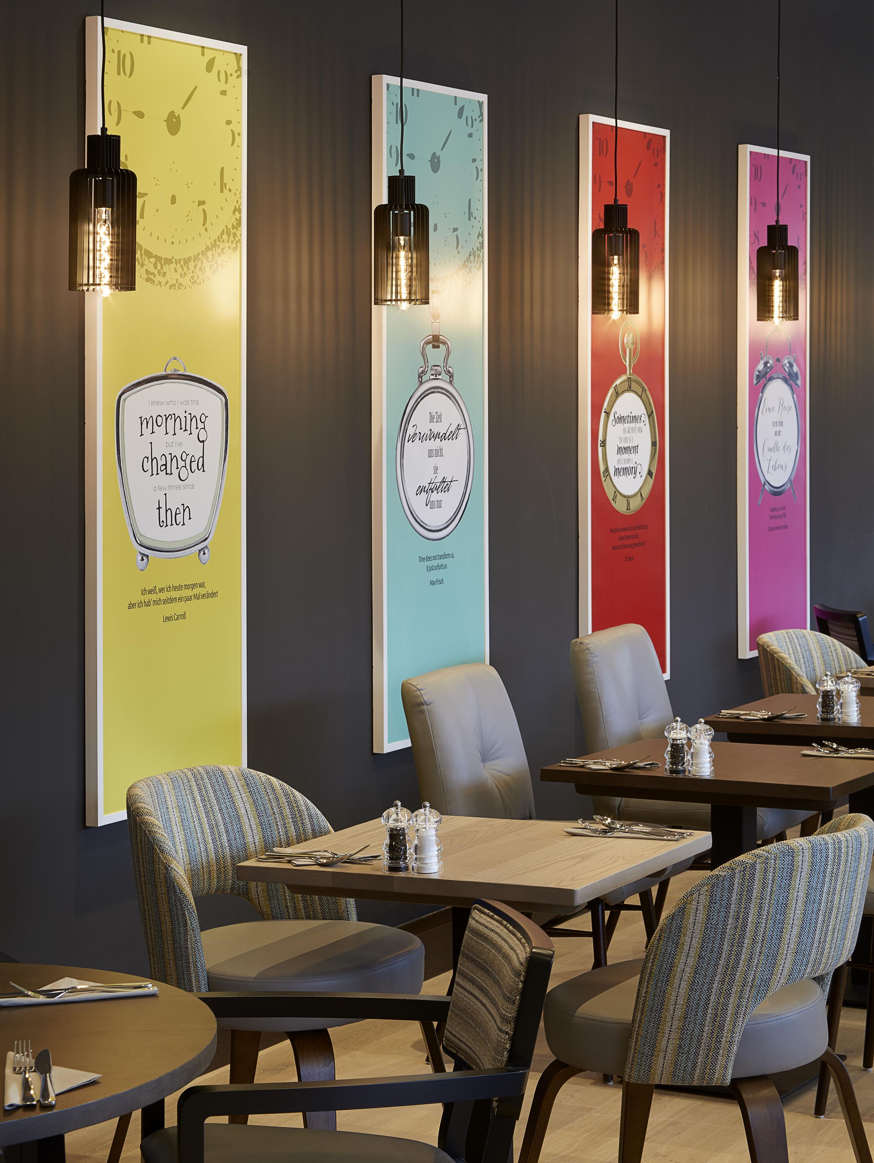 Ein Restaurant mit modernem Interieur, das Tische, Stühle und dekorative Wandbilder zeigt.