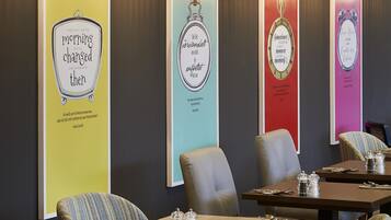 Ein Restaurant mit modernem Interieur, das Tische, Stühle und dekorative Wandbilder zeigt.