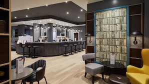 A modern bar area with a counter, bar stools, and a bookshelf with books.