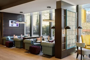 Ein stilvoller Lounge-Bereich mit Sofas, Poufs, einem Bücherregal und einem Fernseher.
