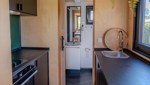 Eine kompakte Küche mit Backofen, Spüle und einem Fenster mit Blick auf Grünflächen.