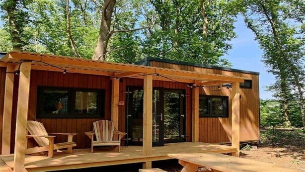 Eine Holzhütte mit einer Laube, zwei Fenstern und einem Picknicktisch.