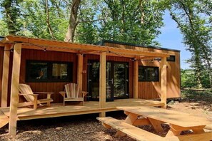 Une cabane en bois dotée d’un porche couvert, de deux fenêtres et d’une table de pique-nique.