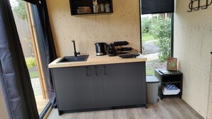 A compact kitchen with a wooden countertop, a black sink, a coffee maker, and a small trash bin. - Cabin in Nature near Scenic Trails (Scherpenzeel (FR))