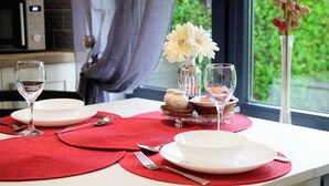 A dining table set with red placemats, white plates, and clear wine glasses.