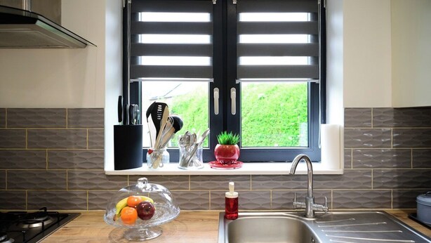A kitchen with a window, a sink, a stove, and a fruit bowl.
