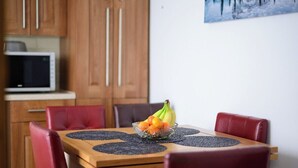 A dining area with a wooden table, red chairs, and a fruit bowl on the table.