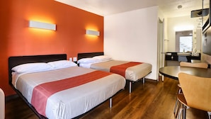 Una habitación de hotel con dos camas, una mesa de comedor y una kitchenette.