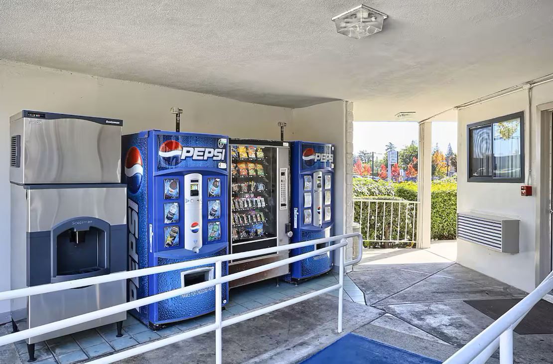 A vending machine area with Pepsi and a water dispenser, a metal railing, and a building entrance.