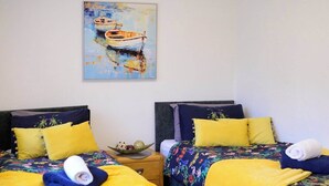 A hotel room with two beds, each with floral-patterned bedding and yellow pillows. There is a painting of a boat on the wall, and a ceiling light fixture is visible. - Strelley House 4 - free parking, WiFi , Netflix, Family & Contractor friendly (Nottingham)
