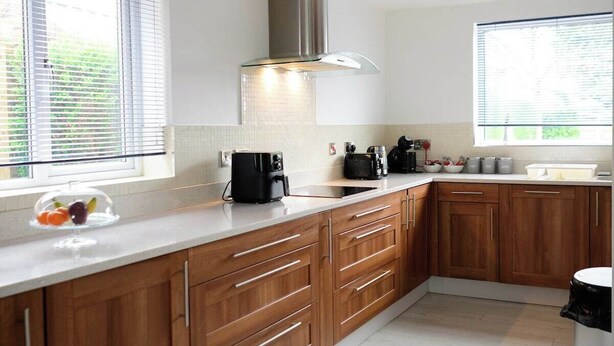 A modern kitchen with wooden cabinets, a stainless steel range hood, and a large window providing natural light. - Strelley House 4 - free parking, WiFi , Netflix, Family & Contractor friendly (Nottingham)