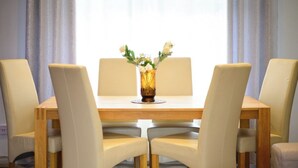 A dining table with four chairs, a vase with flowers, and a window with curtains. - Strelley House 2, off-street parking, Perfect for Family & Contractor friendly (Nottingham)