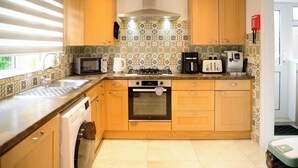 A kitchen with wooden cabinets, a microwave, a stove, a coffee maker, and a dishwasher. - Strelley House 2, off-street parking, Perfect for Family & Contractor friendly (Nottingham)