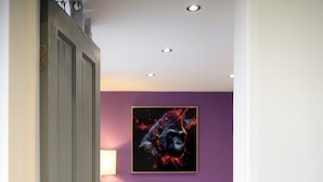 A hallway leading to a bedroom with a purple wall, a bed, and a painting. - Strelley House 2, off-street parking, Perfect for Family & Contractor friendly (Nottingham)