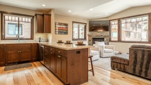 A spacious kitchen with wooden cabinets, a central island, and a stone fireplace. - Hot Tub | Ping Pong Table | EV Charger (Mammoth Lakes)