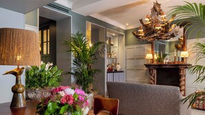 A dining area with a wooden table, a vase of flowers, a lamp, and a chair. - Hôtel Aubépine (Paris)