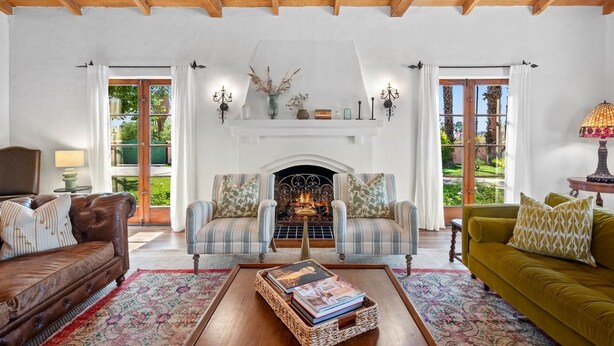 A cozy living room with a fireplace, two armchairs, a sofa, and a coffee table.