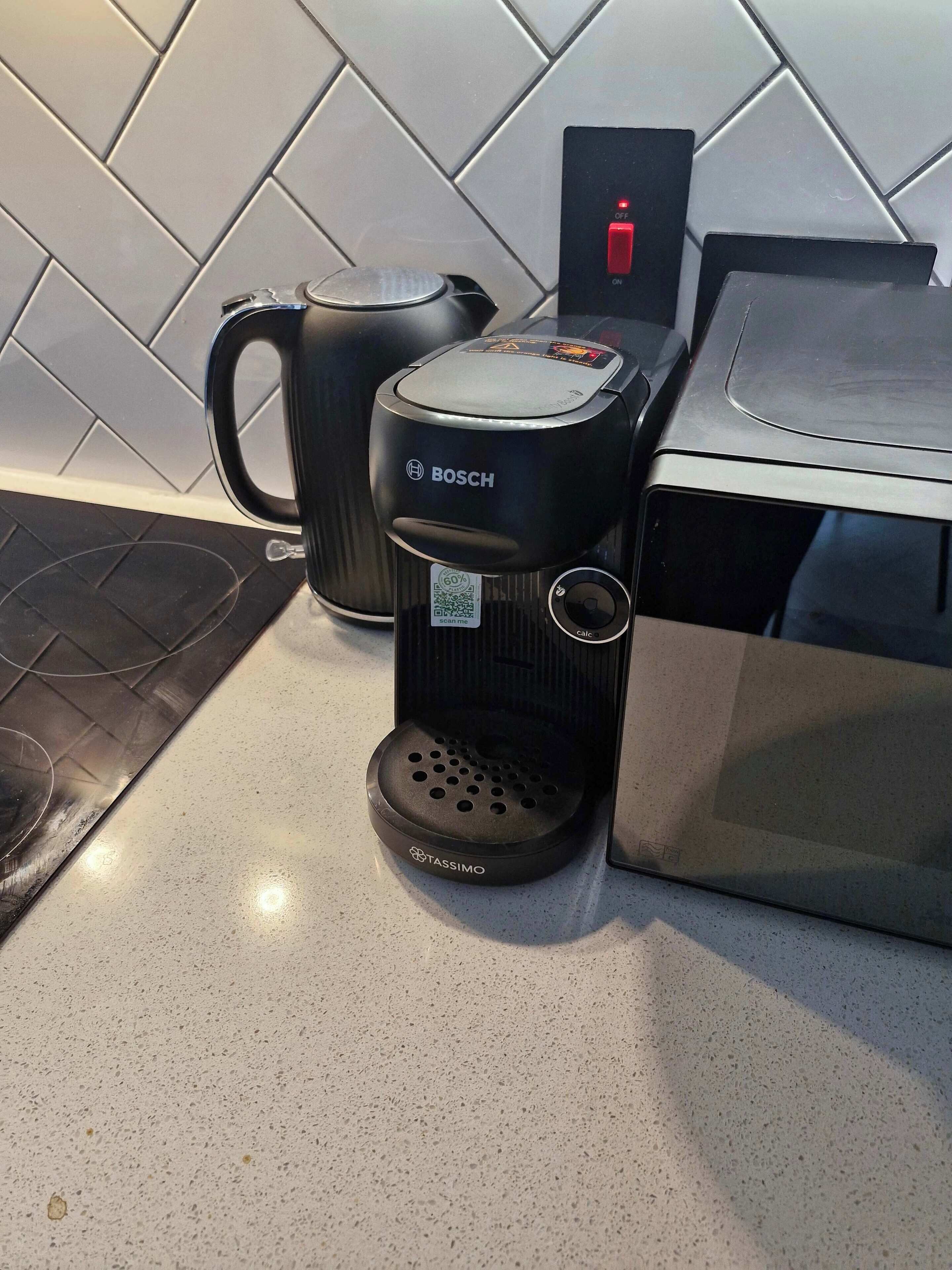 Uma cozinha com cafeteira Bosch, dispensador de cápsulas Tassimo e chaleira sobre bancada.