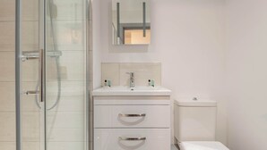 A modern bathroom with a glass shower enclosure, a white sink with a mirror above, and a toilet. - Spacious & Bright 1 Bed Flat in Central Doncaster (South Yorkshire)