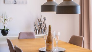 Une table à manger avec une bouteille de vin et des verres, un vase de fleurs et une sculpture métallique décorative.