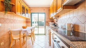 Une cuisine moderne avec des meubles en bois, une table à manger avec des chaises et une vue sur l’extérieur.