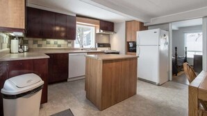 Una cocina compacta con armarios de madera, una isla central, un refrigerador y un microondas.