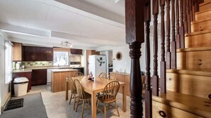 Una cocina moderna con armarios de madera, una isla central y un comedor con mesa y sillas de madera.