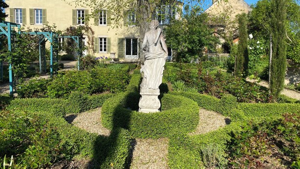 A garden with a statue, neatly trimmed hedges, and a building with green shutters in the background. - 19th century manor house "la belle vie" 14/15 persons 5 min from Beaune (Tailly)