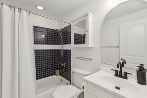 A bathroom with a bathtub, toilet, sink, and mirror. - Free Parking! Large, 2BR/1.5BA with AC/TV/Internet (Washington)
