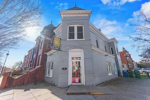 A corner building with a shop on the ground floor, a white door, and a brick facade. - Free Parking! Large, 2BR/1.5BA with AC/TV/Internet (Washington)