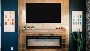 A modern living room with a fireplace, a flat-screen TV mounted above it, and decorative tiles on the wall.