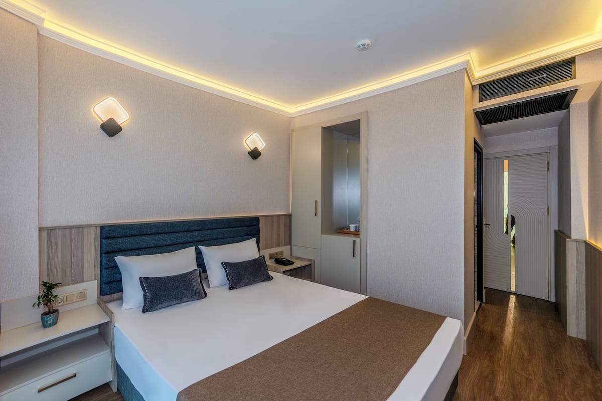 Una habitación de hotel moderna con una cama grande, mesitas de noche, un tocador y un armario.