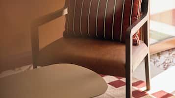 Una silla con cojín y una mesa en una habitación con alfombra estampada.