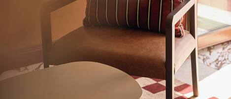 A chair with a cushion and a table in a room with a patterned carpet.