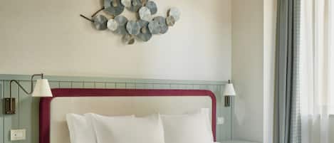 A hotel room with a large bed, a chandelier, a decorative wall piece, and a nightstand with a lamp.