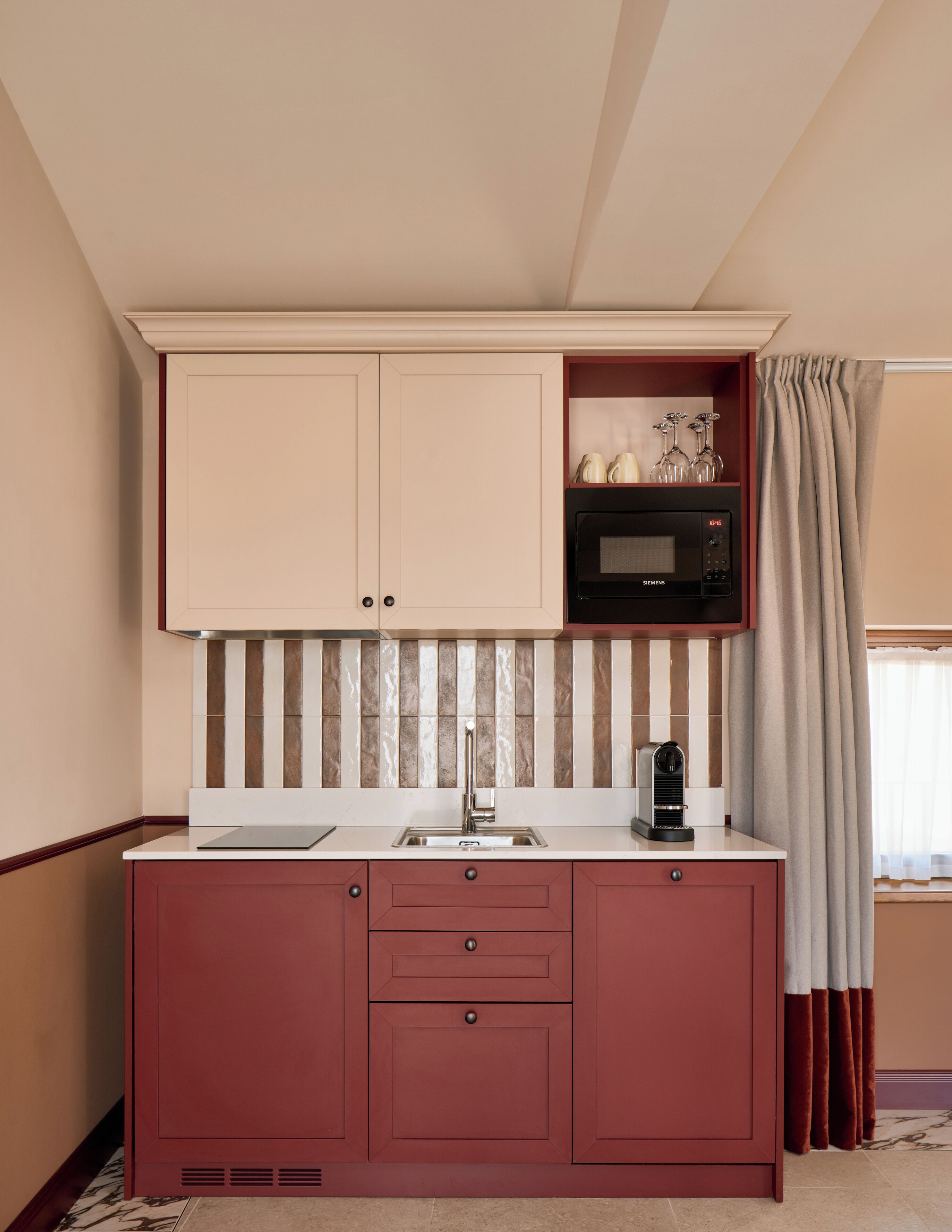 Una kitchenette compacta equipada con microondas, cafetera y un porta vasos para vino.