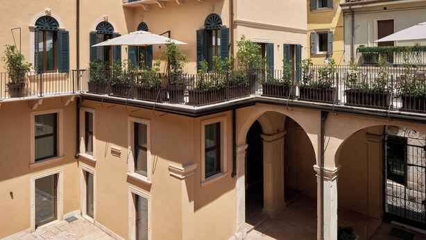 A multi-story building with balconies, a covered walkway, and a courtyard with potted plants. - Homy Livia Verona (Verona)
