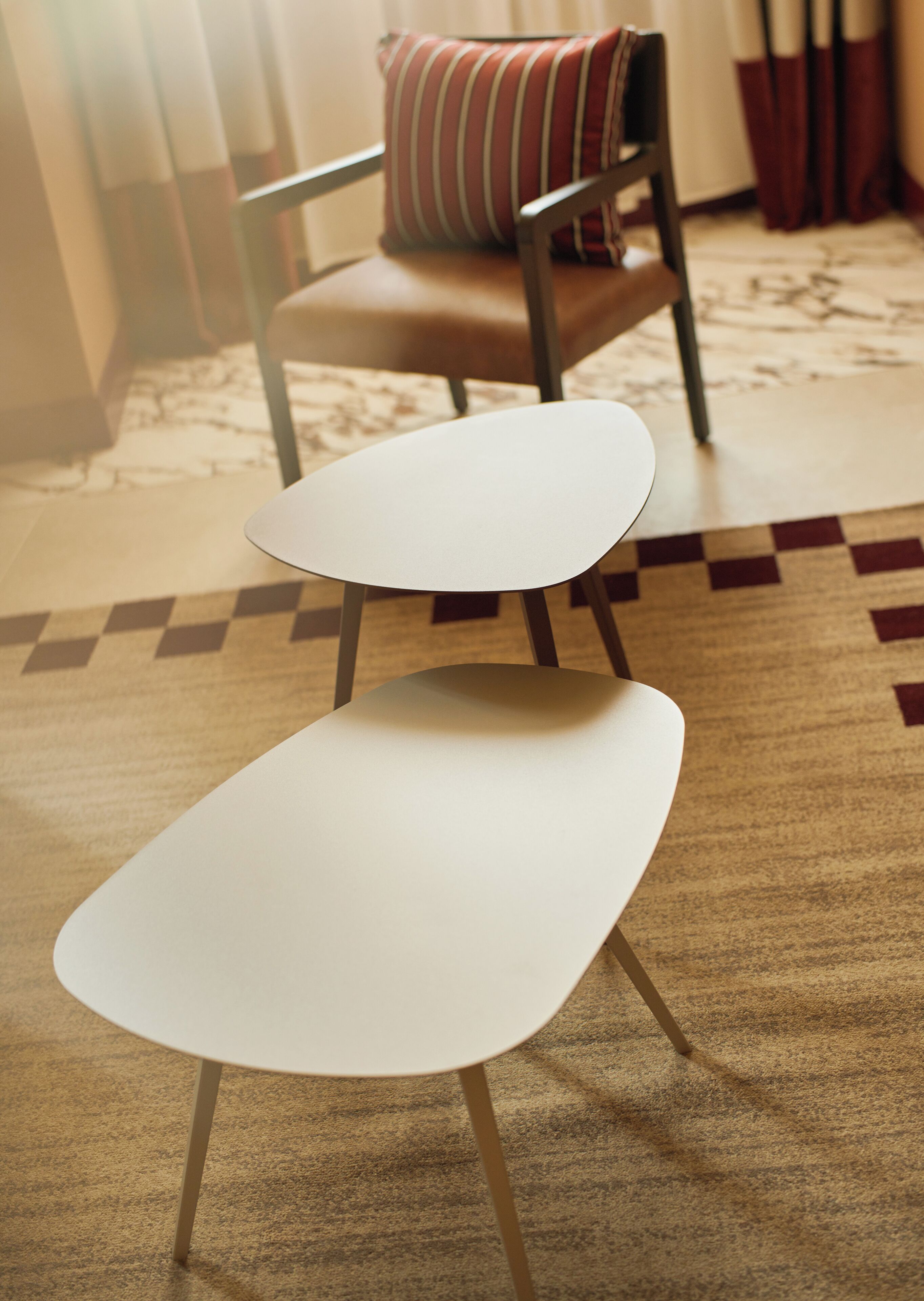 Two white chairs with metal legs on a patterned carpet.