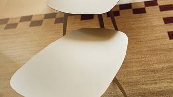 Two white chairs with metal legs on a patterned carpet.