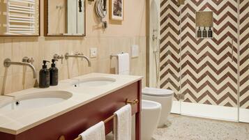 A modern bathroom with two sinks, a large mirror, and a shower area.