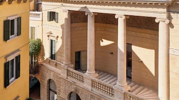 Un patio con un edificio que presenta columnas clásicas, arcos y un tejado de tejas.