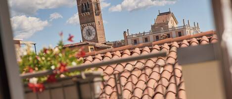 A balcony with terracotta tiles, a striped chair, and a view of a historic tower.