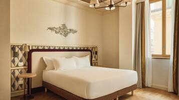 Une chambre à coucher avec un lit, un lustre, une lampe fixée au mur et un mur orné d’un motif géométrique.