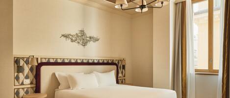 A bedroom with a bed, a chandelier, a wall-mounted lamp, and a geometric-patterned wall.